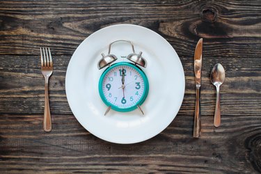Intermittent fasting concept featuring an alarm clock on a plate