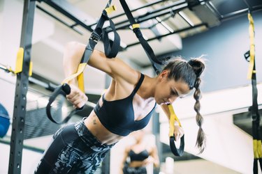 Young woman doing suspension traning in the gym