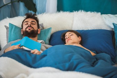 Couple sleeping in comfortable bed, covered with cozy blankets