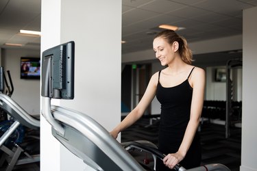 Woman turning on treadmill before workout