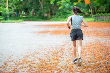 年轻的跑步女子在公园跑步的背影。