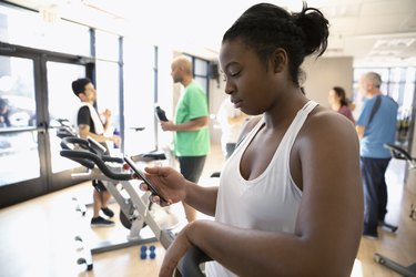 Woman using smart phone after exercise class in gym