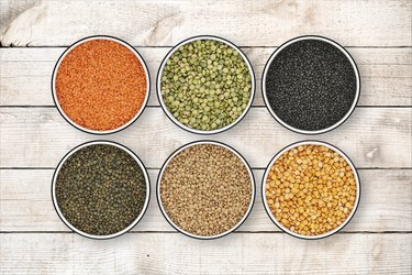 Six lentil bowls on wood background from directly above