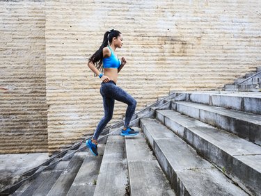 Female runner moving up on stone stairs-side view