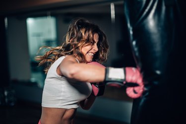 close up of a woman punching a boxing bag hard