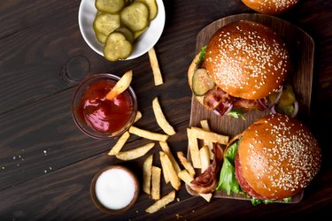 Burger and french fries on wooden table.