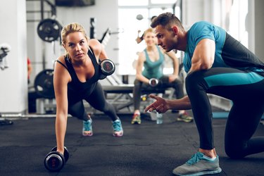 Sporty woman doing push-ups under supervision of personal trainer