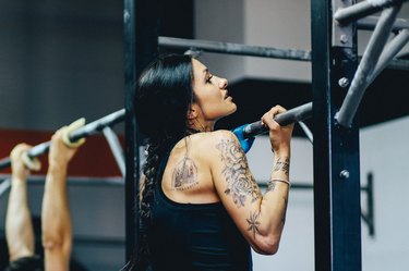 Young woman doing chin-ups on crosstraining training