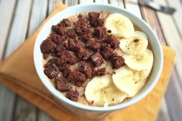 Bowl of cereal topped with sliced bananas and brownie pieces.