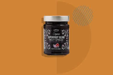 A jar of Thrive Market Organic Superfruit Blend Fruit Spread staged on an orange background