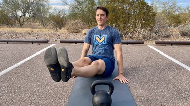 Man doing an ab workout with a kettlebell in the parking lot