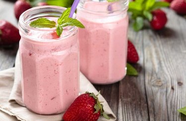 pink Fruit Smoothie in glass jar on table with strawberries