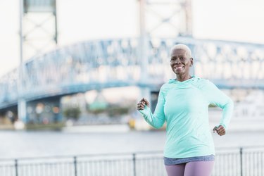 woman in teal shirt and purple leggings running outside