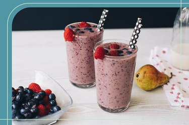 Two glasses of healthy berry smoothies on a kitchen counter with polka-dot straws