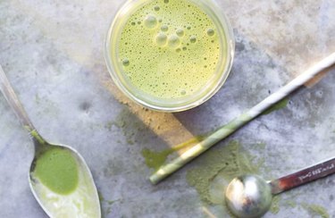 Anti-inflammatory Drink Energizing Green Smoothie in glass with straw and spoons