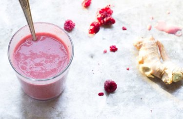 Anti-inflammatory Drink Ginger-Berry Smoothie in a glass with spoon and ginger root
