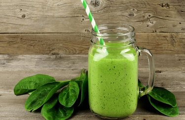 Anti-inflammatory drink Jasmine Green Sunrise Smoothie in a mason jar with a straw and spinach leaves