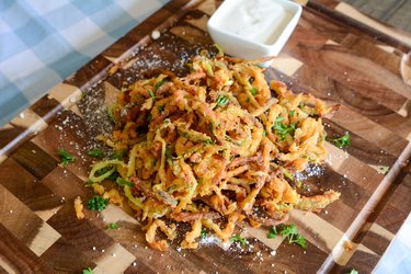 Air Fryer Veggie Curly Zucchini Fries on a wood serving board with a white dipping sauce