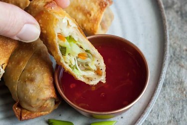Air Fryer Veggie Egg Rolls on a white plate with red dipping sauce