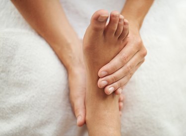 close view of hands checking a person's pulse on the top of their foot