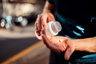 Close up of hands taking a vitamin or supplement from bottle