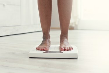 woman's feet on a bathroom scale, measuring her weight loss from the first week of WW