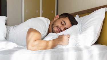 Young man sleeping on his stomach in bed