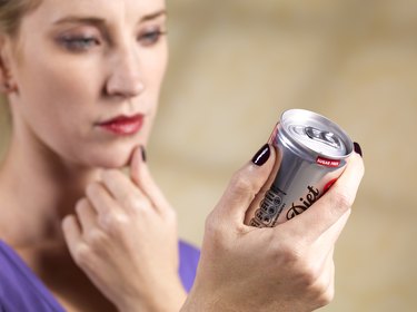 Woman reading ingredients list on a diet soda can