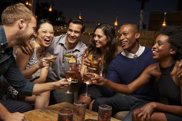 Group Of Friends Enjoying Night Out At Rooftop Bar