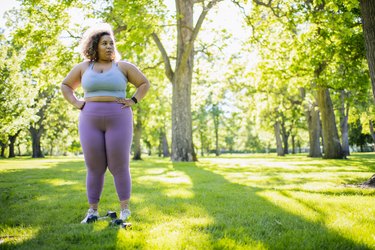 Young woman resting while working out with hand weights outdoors, doing the best strength exercises for beginners with obesity