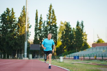 Person wearing a blue T-shirt and black shorts doing a track workout outside.