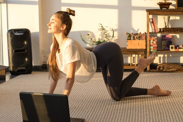 一个白人女人在日出时在地板上做猫牛伸展运动