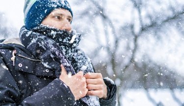 close up of person's face with scarf covered by snow on a winter day