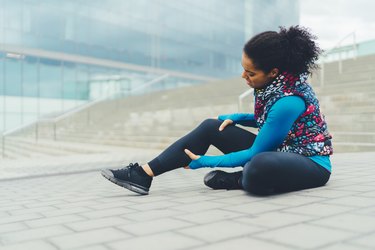 女运动员与骨折的腿坐在地面上,巴塞罗那