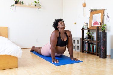Person in a larger body doing the cobra pose, a yoga for sciatica move, at home