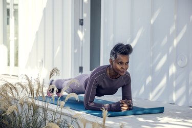 A person in their 40s in a plank position on an exercise mat