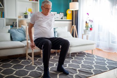 older man getting up out of chair in a modern living room