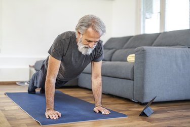 Mature Man Stretching at Home on Exercise Mat