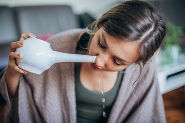 A woman doing nasal irrigation as a natural remedy for sore throat