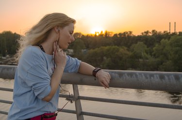 女人检查脉搏和心脏病她聪明看户外运动后慢跑在城市桥梁。照顾心跳培训