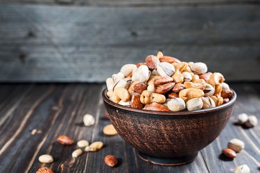 Nuts set in bowl almonds, pistachios, cashews, peanuts, vintage wooden background