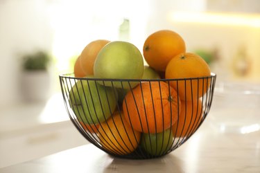 Bowl of delicious fresh fruits on table in kitchen