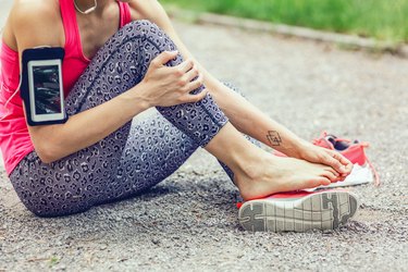 a person in athletic clothes sitting on the ground and rubbing their bare feet because they have numb toes