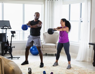 couple doing kettlebell swings in their living room