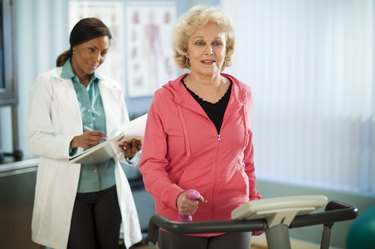 older woman with COPD walking on a treadmill while a doctor takes notes