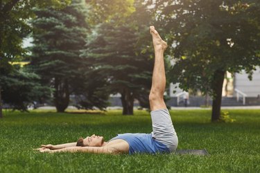 Man lying down doing lower abs exercise outdoors