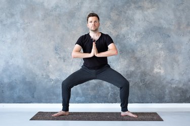 man doing a bodyweight sumo squat exercise on a yoga mat
