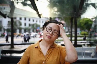 a woman sitting on a bench outside and looking sad but not crying