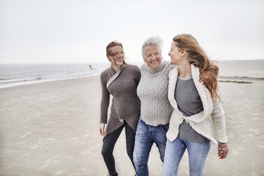 Grandmother, mother and daughter walking on the beach