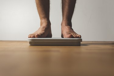 Low Section of person Standing On Weight Scale Over Hardwood Floor At Home